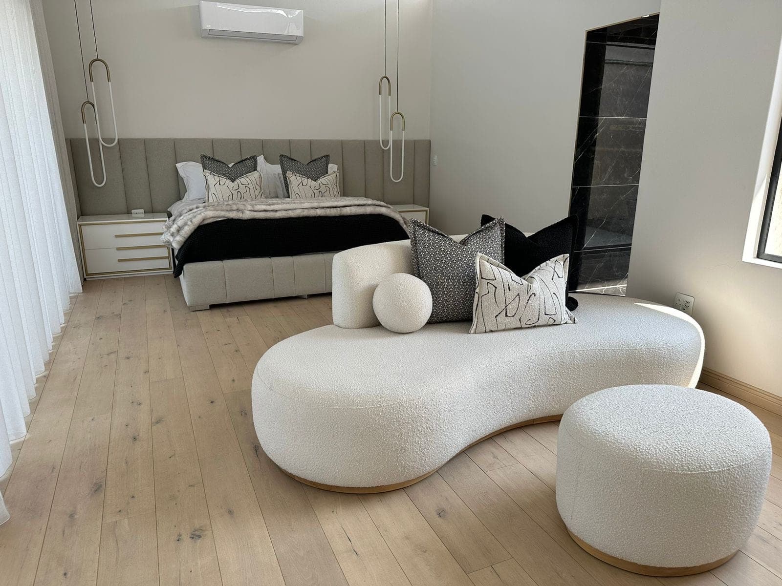 Curved boucle chaise and ottoman in a bright bedroom