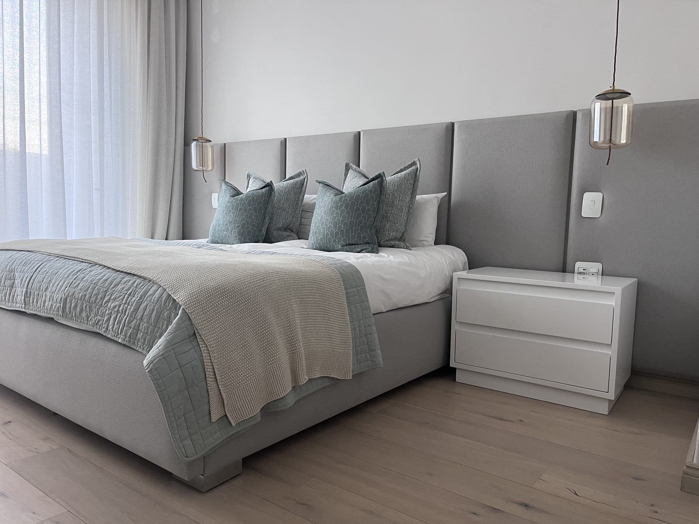 Wall-to-wall panelled headboard with pendant lighting